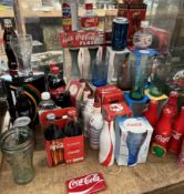 A collection of Coca Cola memorabilia including bottles, glasses,