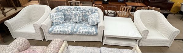 A white painted wicker three piece suite together with a coffee table