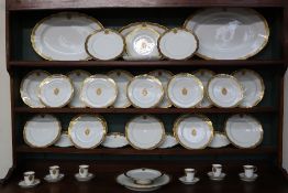 An extensive French porcelain part dinner service with a gilt decorated rim and oval coat of arms