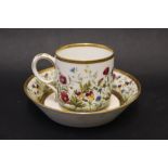 A 19th century French porcelain coffee can and saucer decorated with flowers and leaves to a thick