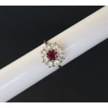 A ruby and diamond cluster ring set with a central ruby surrounded by eight brilliant cut diamonds