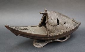 A bronze model of a boat with a removable canopy, seated upon waves,