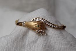 An 18ct yellow gold hinged bangle in the form of a hand,