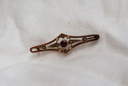 A 15ct yellow gold garnet and seed pearl brooch, set with a round faceted garnet and seed pearls,