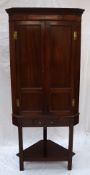 A 19th century mahogany corner cupboard with a moulded dentil cornice and a pair of panelled