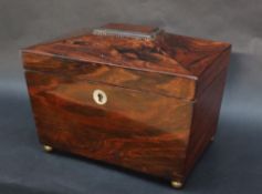 A Victorian rosewood sarcophagus tea caddy, with a reeded top on four brass ball feet,