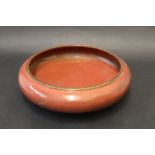 A Japanese Cloisonne bowl with a red ground decorated with scrolls, flowers and leaves,