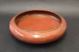 A Japanese Cloisonne bowl with a red ground decorated with scrolls, flowers and leaves,