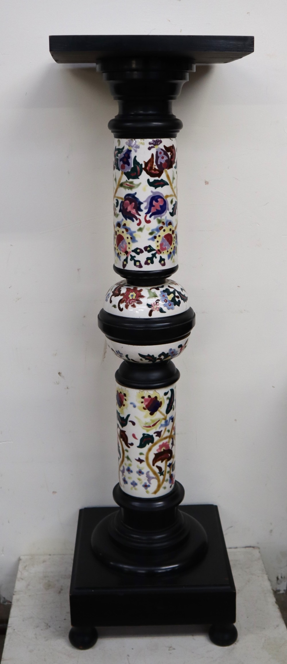 A Zsolnay Pecs pottery and ebonised jardiniere stand with a square top above a floral decorated