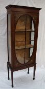 An Edwardian mahogany display cabinet with a moulded cornice above a glazed door and sides on