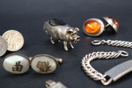 A white metal pin cushion in the form of a pig, 5cm long together with a silver ingot,