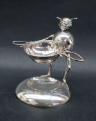 A novelty silver tea strainer holder in the form of a goblin on a circular dished base with a