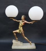 An Art Deco style table lamp with a gilt decorated maiden holding aloft a pair of white globe