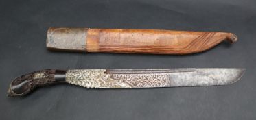 An Indonesian dagger with a carved and white metal mounted handle,