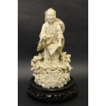 A Chinese Blanc de Chine porcelain figure of a bearded man holding a shoe, standing amongst shells,