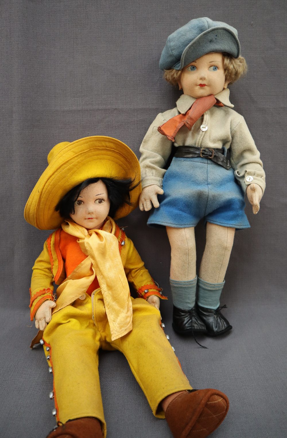 A felt doll with black hair, brown eyes and painted lips dressed as a cow girl,