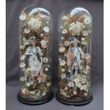 A pair of 19th century continental porcelain figures surrounded by porcelain flowers under glass