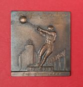 A square bronze plaque depicting a hammer thrower standing on a plinth "Beograd" incised to the