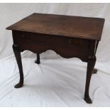 An 18th century oak lowboy with a rectangular planked top above a frieze drawer and shaped apron on