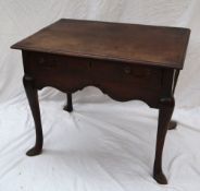 An 18th century oak lowboy with a rectangular planked top above a frieze drawer and shaped apron on