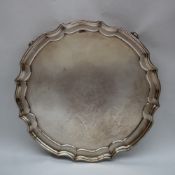 A George V silver salver of circular shaped form on four scrolling feet, Sheffield, 1935,