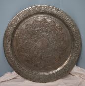 A Persian white metal table top / charger decorated with scrolls and leaves,