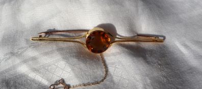 A 15ct gold citrine set bar brooch, with a central round faceted citrine to a shaped bar,