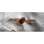 A 15ct gold citrine set bar brooch, with a central round faceted citrine to a shaped bar,