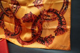 Cartier, a silk scarf, with interlocking leopards head bracelets to an orange ground, boxed,