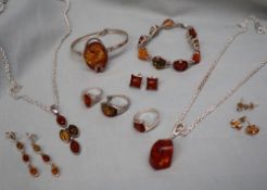 A collection of amber and white metal jewellery including bracelets, pendants, rings,