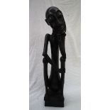 An African carving of a seated figure with his head resting on his right hand on a square plinth,