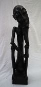 An African carving of a seated figure with his head resting on his right hand on a square plinth,