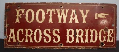 A brown and cream enamel sign "Footway across bridge" and a pointing finger,