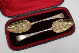 A pair of George III silver berry spoons, the oval bowls embossed with fruit and leaves,