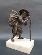A bronze model of an elderly man with an open sack on his back,