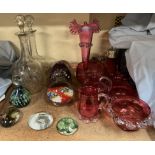 A cranberry glass vase with a flared rim together with assorted cranberry glass, glass decanters,