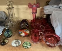 A cranberry glass vase with a flared rim together with assorted cranberry glass, glass decanters,