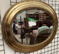 A large gilt decorated oval wall mirror with a bevelled plate,