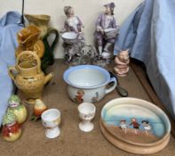 A pair of continental figures, in purple outfits holding baskets, together with pottery jugs, cruet,