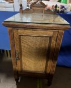 An Arts and crafts style oak bedside cabinet with a cresting rail and a single panelled door