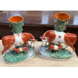 A pair of Staffordshire cow and calf spill vases