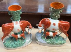 A pair of Staffordshire cow and calf spill vases