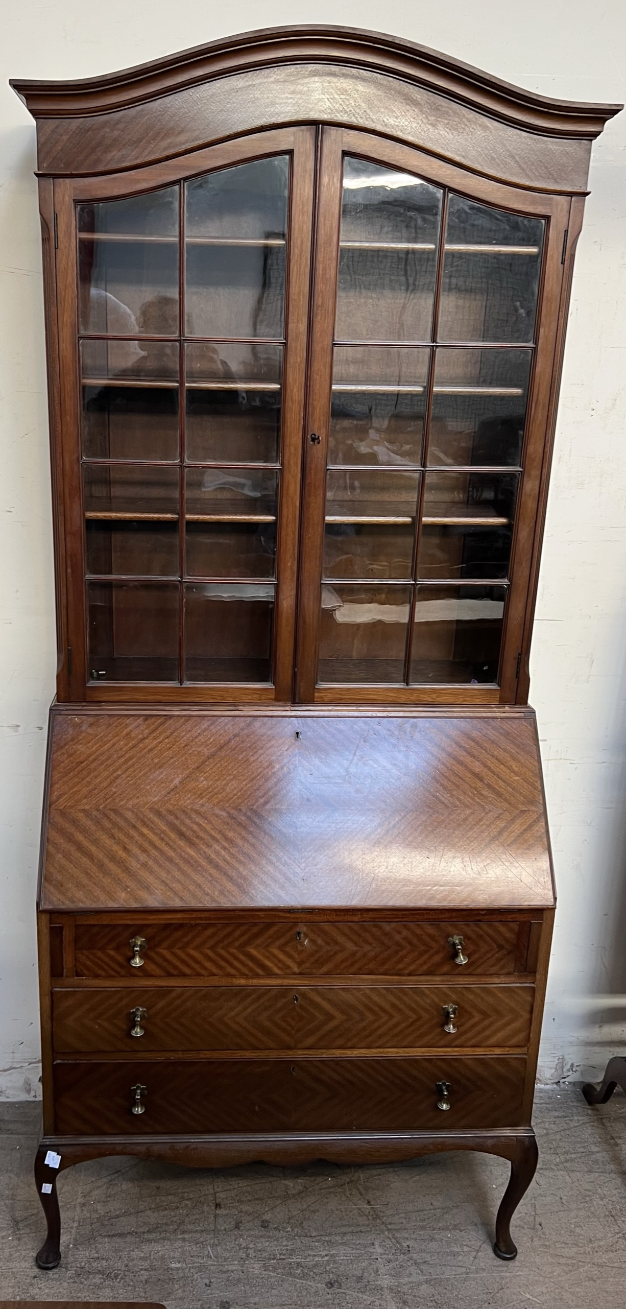 A 20th century mahogany bureau bookcase with an arched cornice above a pair of glazed doors,