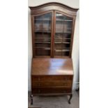 A 20th century mahogany bureau bookcase with an arched cornice above a pair of glazed doors,