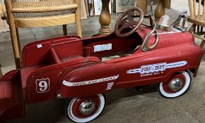 A fire engine pedal car with bell and light on the bonnet,