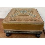 A 19th century woolwork decorated foot stool with a square top on tuned legs
