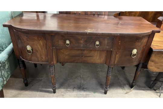 A Regency mahogany sideboard with a shaped top above two central drawers,