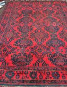 A red ground rug, with stylised blue flower heads and multiple guard stripes,