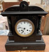 A black slate mantle clock, with a shaped top and columns,