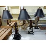 A pair of modern decorative table lamps modelled as suited monkeys holding lights aloft with metal